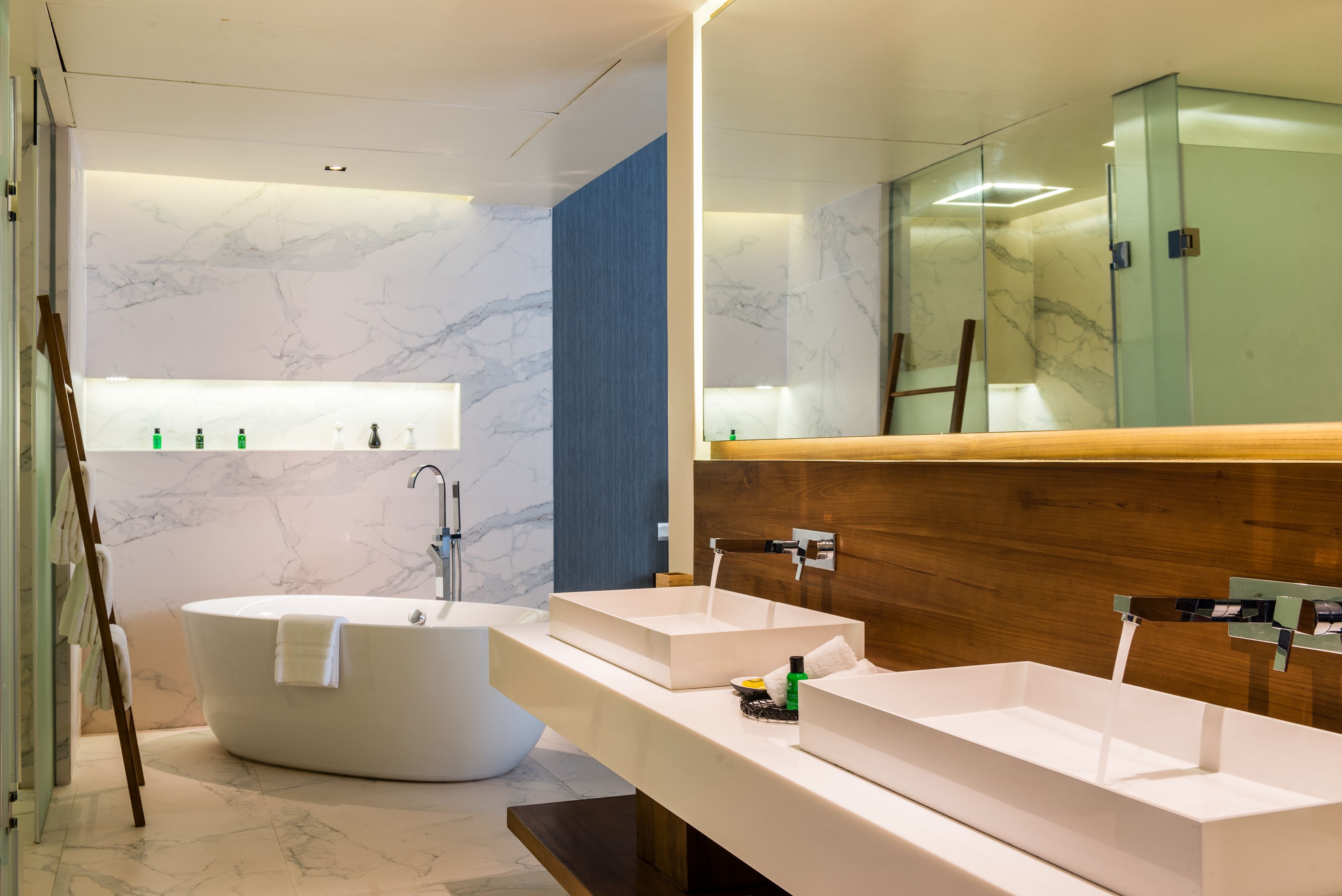 A modern bathroom with a freestanding bathtub, two sinks, and a large mirror.