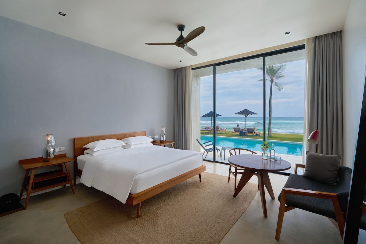 Una habitación de hotel con cama, escritorio, silla, mesa y vista al océano.