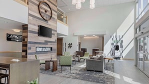 Un hall d’hôtel moderne avec un comptoir d’accueil, un espace salon et une grande horloge murale.