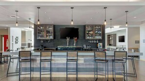 A modern kitchen with a bar area, featuring a flat-screen TV, bar stools, and a variety of kitchen appliances. - Best Western Plus Peppertree Nampa Civic Center Inn (Nampa)