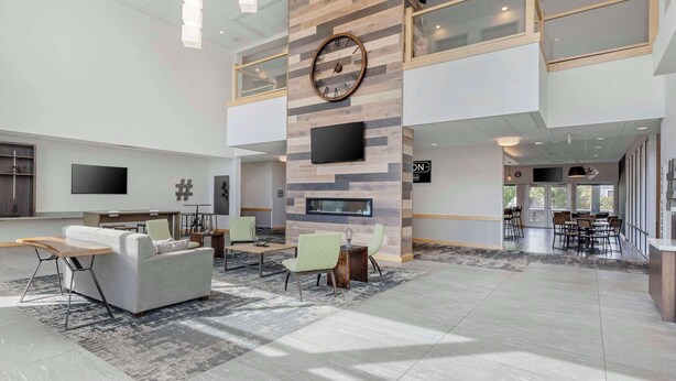 A spacious lobby with a modern design, featuring a large wooden wall with a clock, seating areas, and a TV screen. - Best Western Plus Peppertree Nampa Civic Center Inn (Nampa)