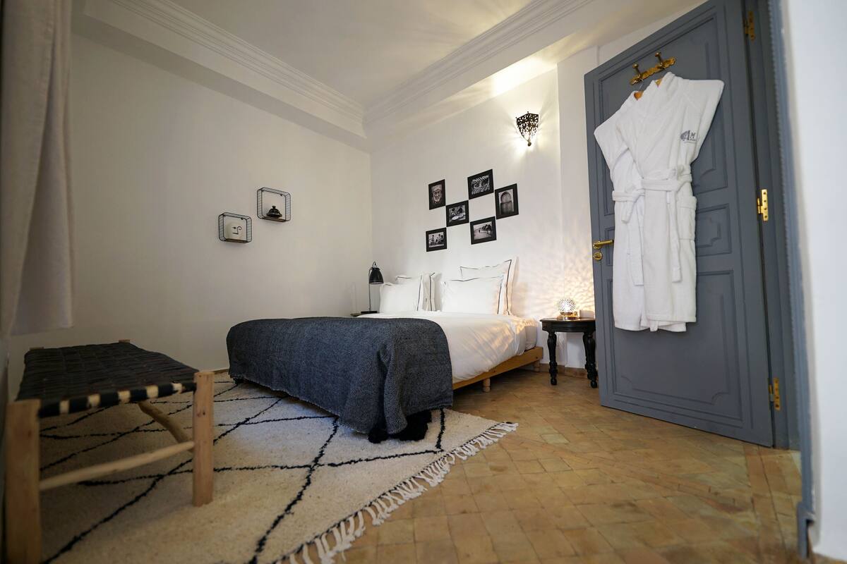 Quarto com cama, mesa de cabeceira e roupão pendurado.