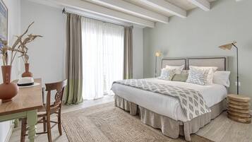 A bedroom with a bed, a desk, and a chair. There is a window with curtains, a lamp, and a rug.