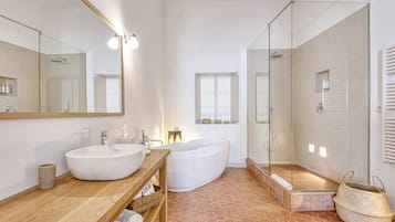 A modern bathroom with a large white sink, a freestanding bathtub, and a glass-enclosed shower area.
