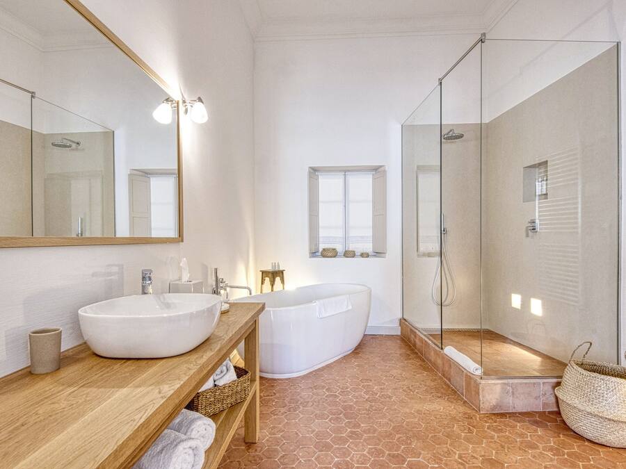 A modern bathroom with a large white sink, a freestanding bathtub, and a glass-enclosed shower area.