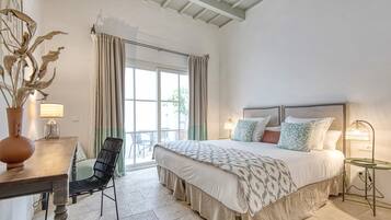 A bedroom with a large bed, a chair, a table, and a lamp.