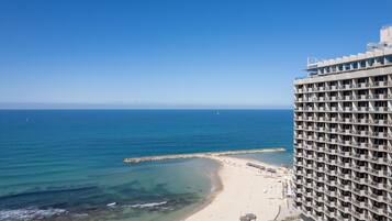 Un hotel moderno de gran altura con varios balcones con vistas a una playa y al océano.