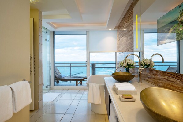 A modern bathroom with a large sink, a bench by the window, and a view of the sea. - The Vista at Hilton Tel Aviv (Tel Aviv)