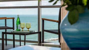 A table with a bottle and glasses, overlooking a beach.