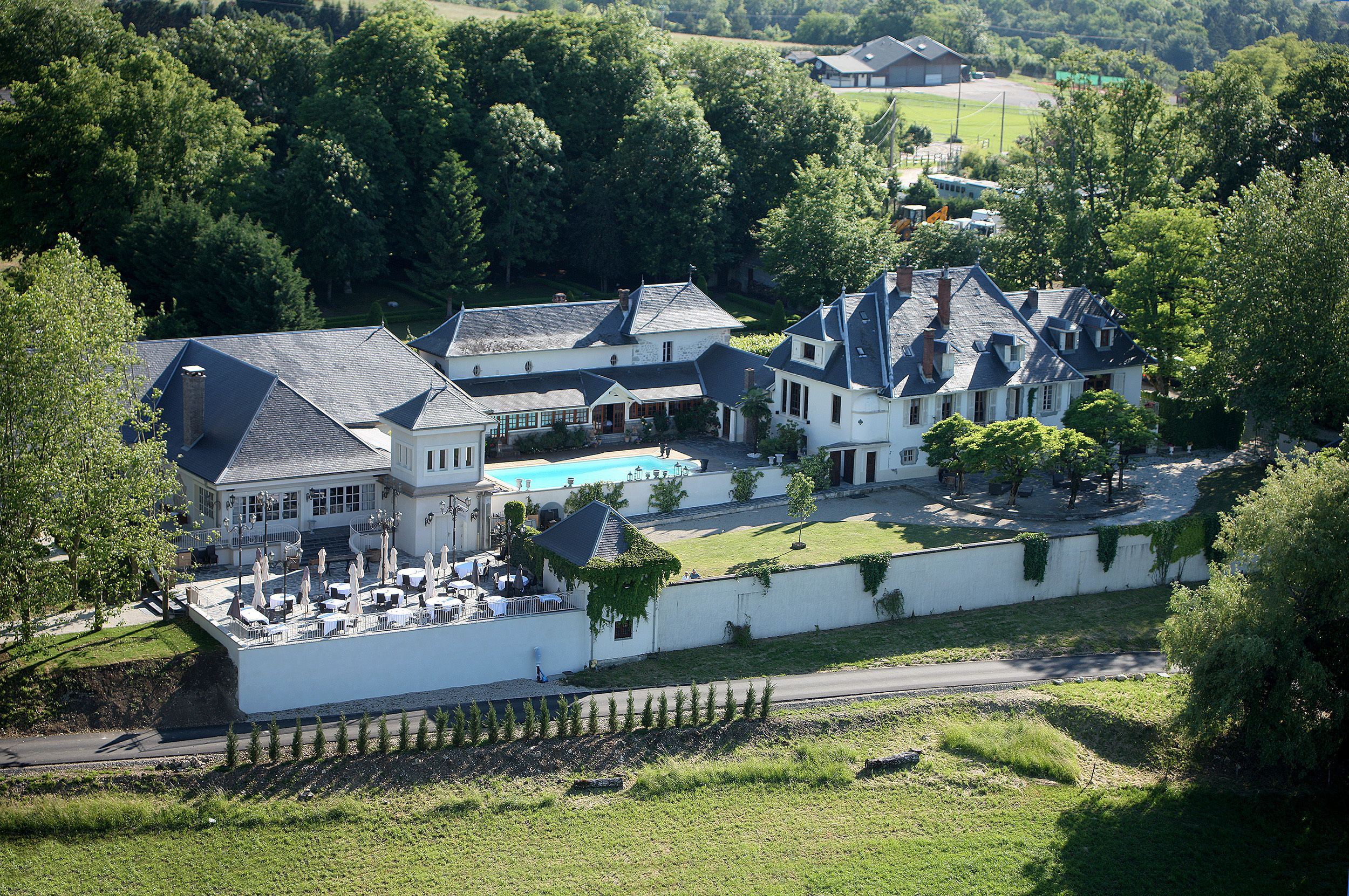 Un vaste domaine comprenant plusieurs bâtiments, une piscine et une pelouse bien entretenue.