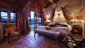 Een slaapkamer met een groot bed, een stoel, een bankje, een nachtkastje en een lamp.