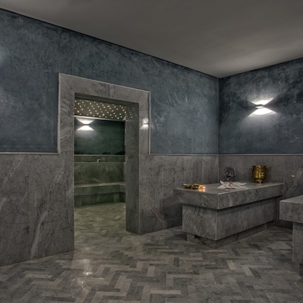 A modern bathroom with marble walls, a herringbone floor, and two sinks with decorative items.