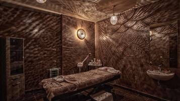 Sala de spa com mesa de massagem, pia e espelho.