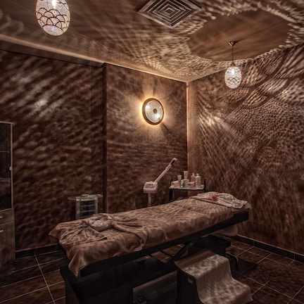 A spa room with a massage table, a sink, and a mirror.