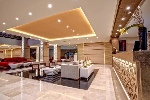 A modern lobby with a reception desk, seating area, and a staircase.