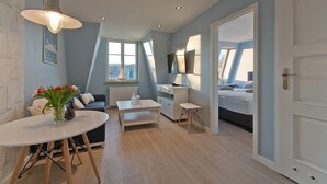 A modern, well-lit room with a dining table, sofa, and a bed. - Imperial Apartments - Valor (Sopot)