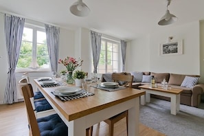 A dining area with a wooden table set for four, striped curtains, and a sofa with striped cushions. - Imperial Apartments - Valor (Sopot)