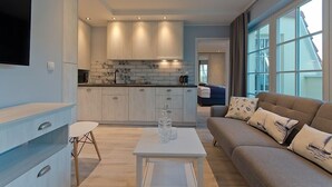 A modern living room with a sofa, a coffee table, and a TV mounted on the wall. - Imperial Apartments - Valor (Sopot)