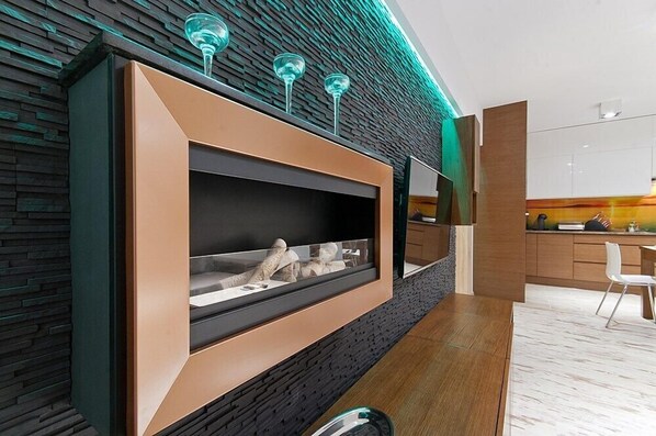 A modern interior with a built-in fireplace, a kitchen area, and a dining space. - Imperial Apartments - Sopocka Przystan (Sopot)