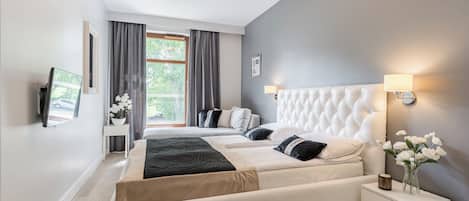 A modern bedroom with a large bed, bedside tables, a wall-mounted TV, and a window with curtains.