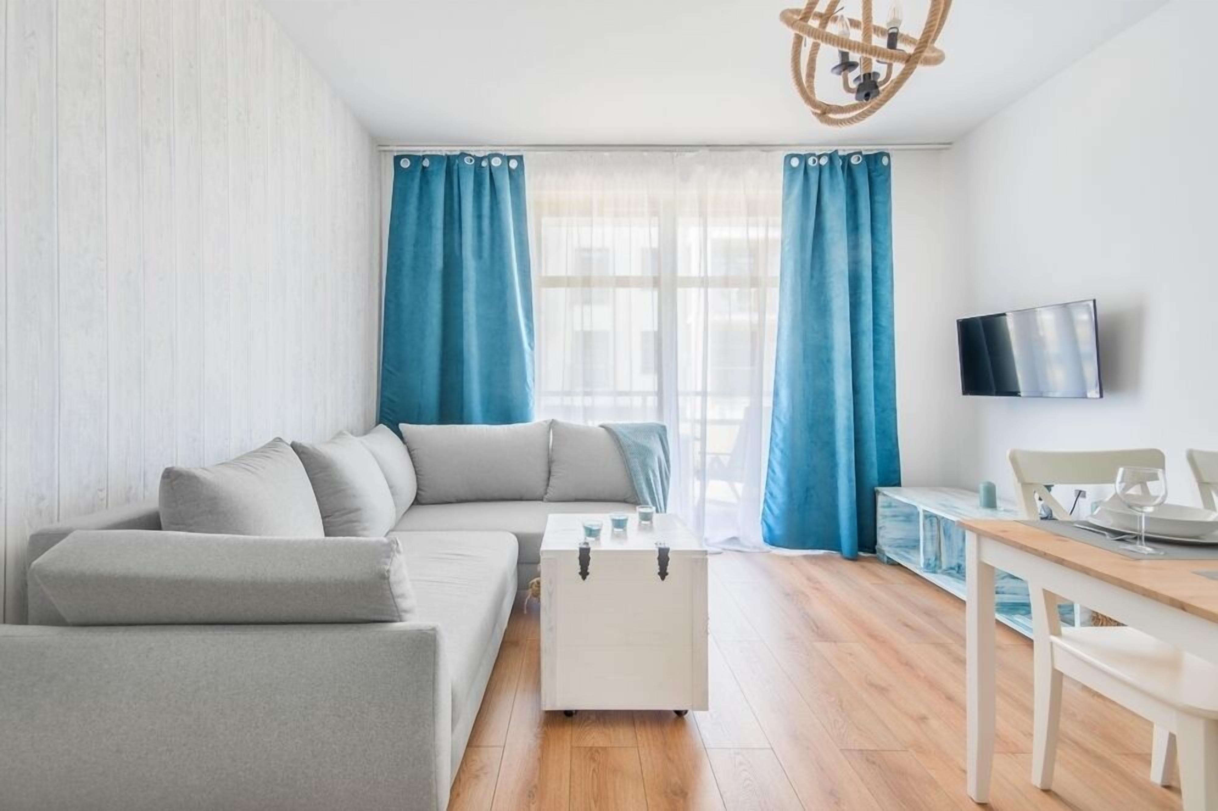 A modern living room with a grey sofa, a white coffee table, and a TV mounted on the wall.