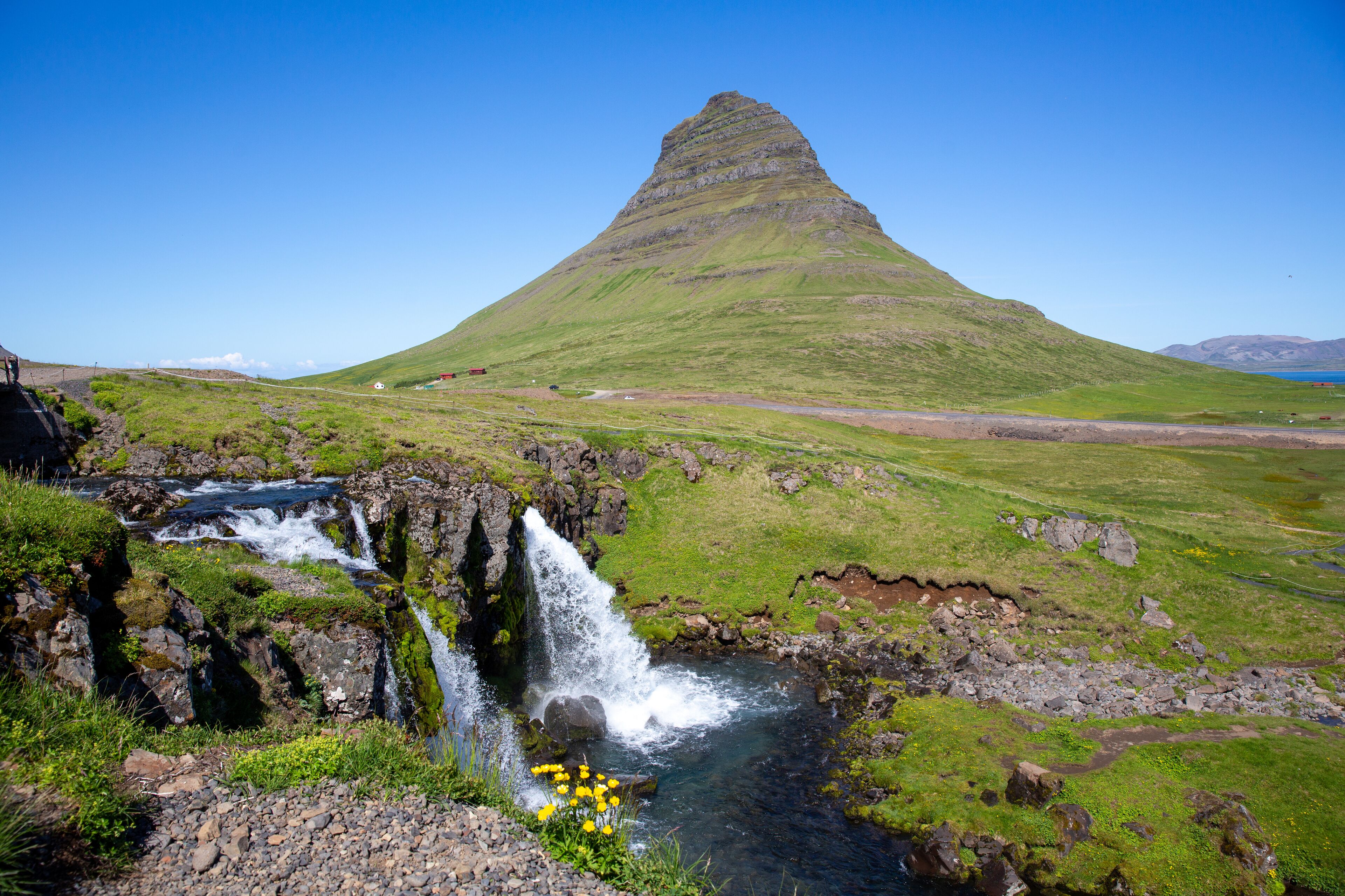 Ein Wasserfall, eine grüne Landschaft und ein Berg.