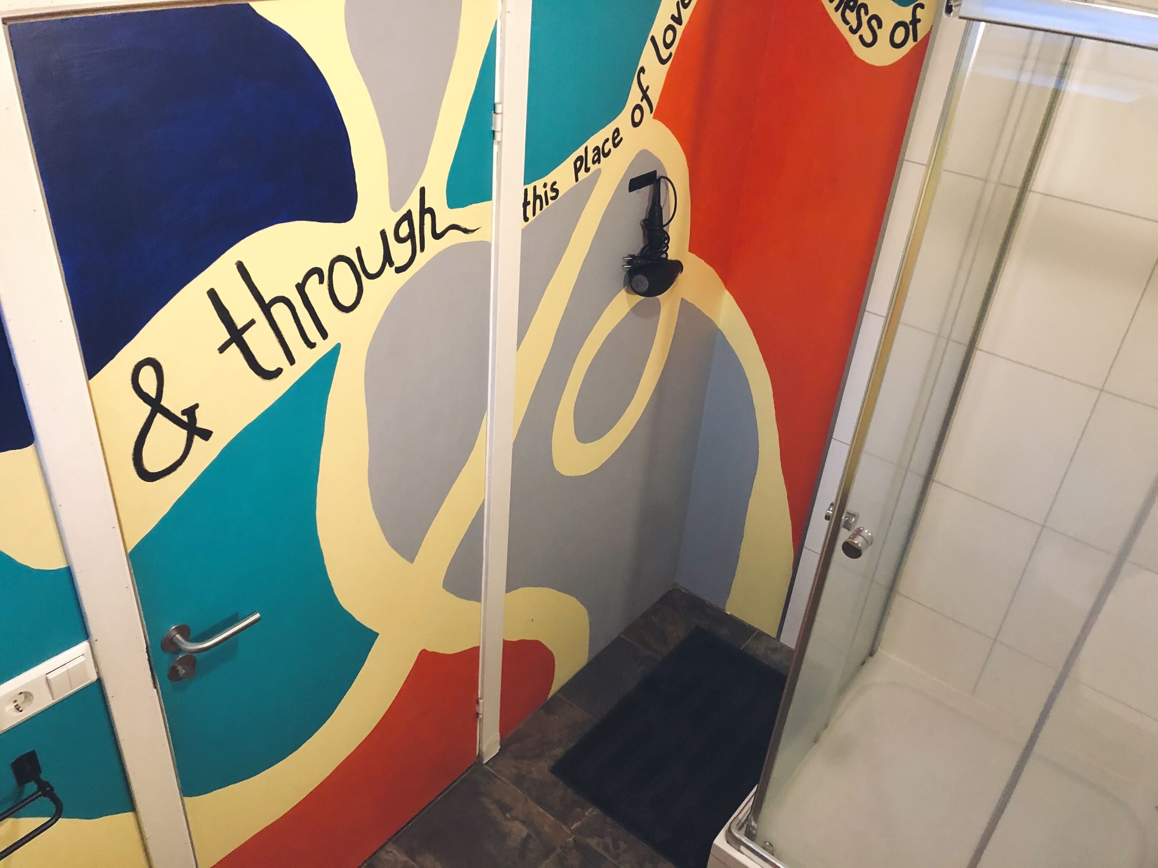 A bathroom with colorful wall art and a shower area.