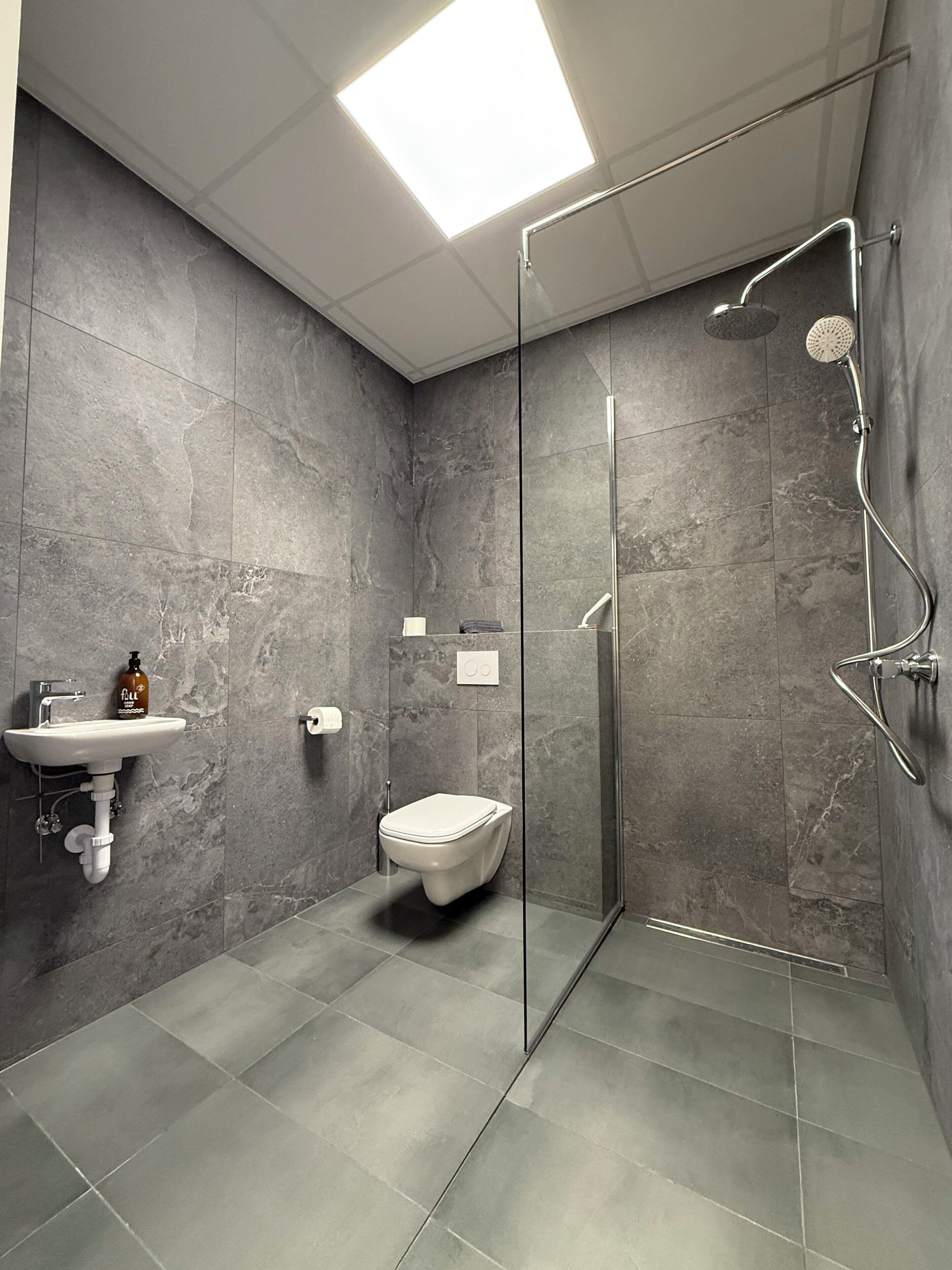 A modern bathroom with a glass shower enclosure, a sink, and a toilet.