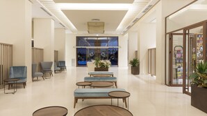 A modern lobby with seating areas, a reception desk, and a view of the outside.