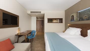 Una habitación de hotel con cama, escritorio, silla y televisor.