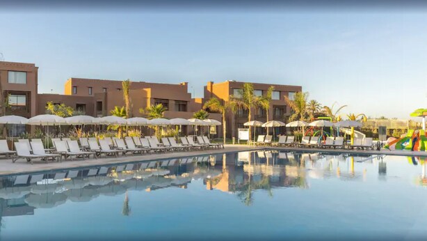 A pool area with lounge chairs and umbrellas, surrounded by buildings with a modern architectural style.