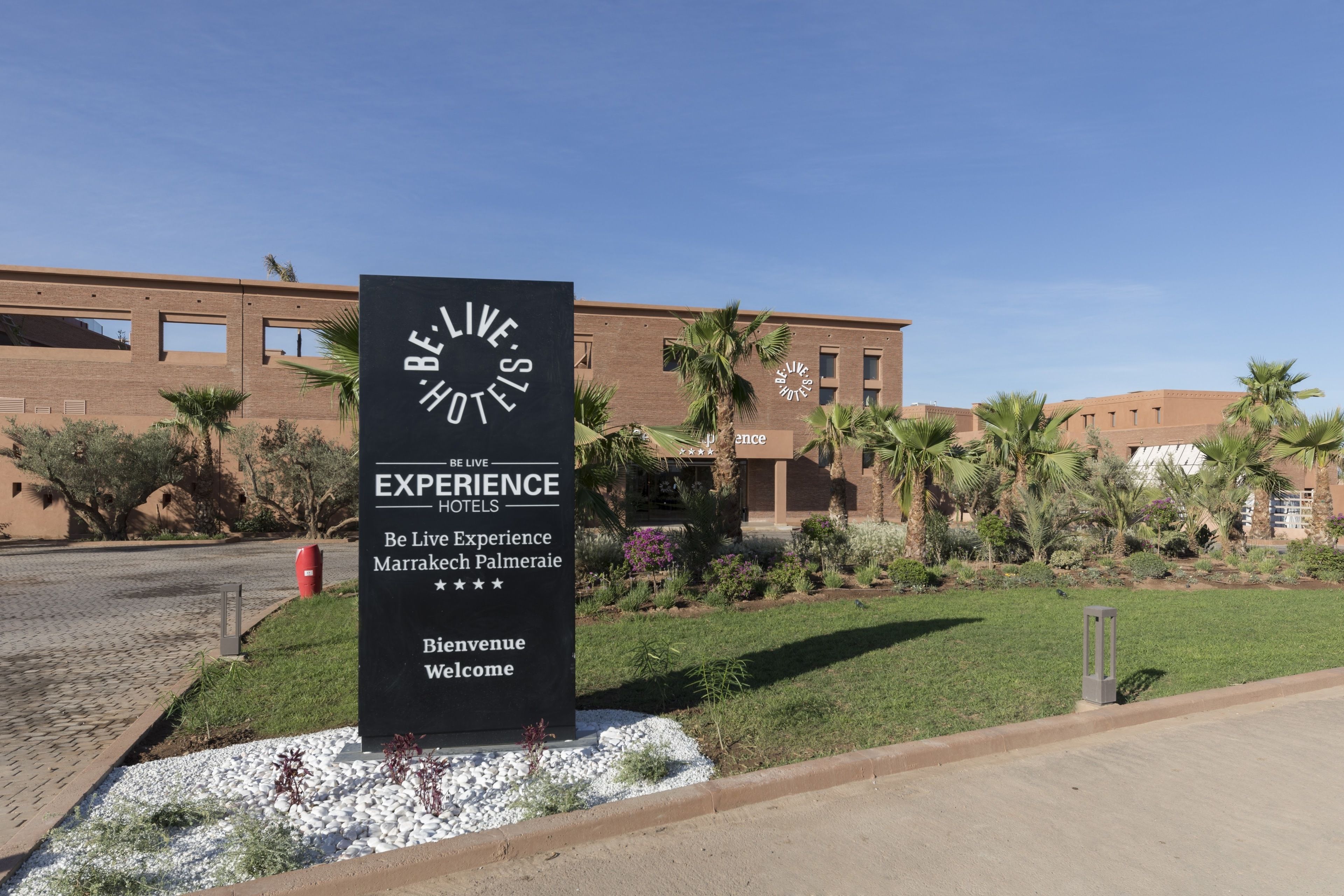 Une enseigne d’hôtel portant le nom « Be Live Experience Hotels » et l’inscription « Marrakech Palmeraie ».