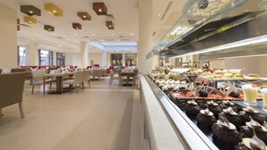A buffet area with various food items and a seating area with tables and chairs.