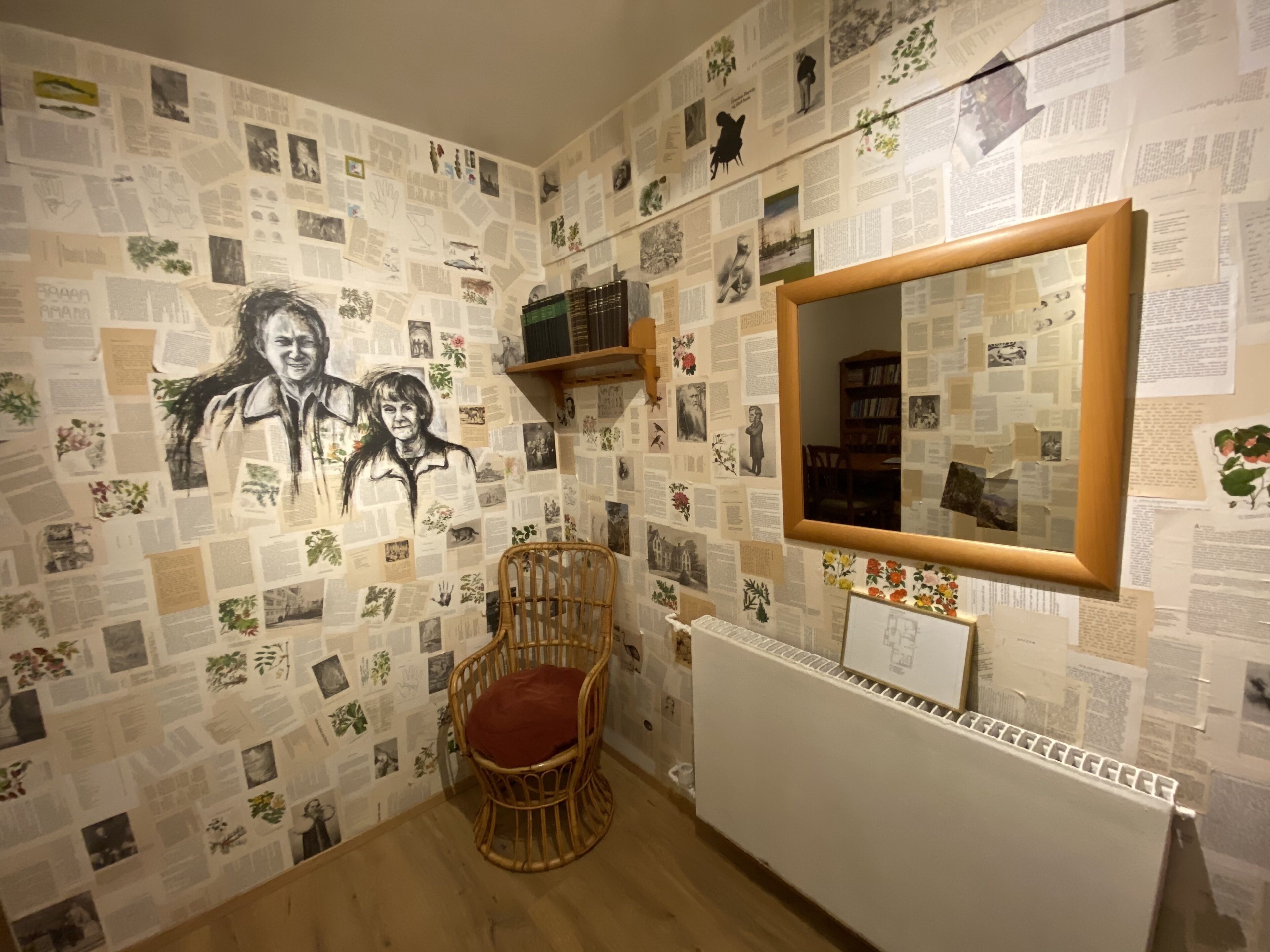 A room with a wall covered in various papers and photographs, a wooden chair with a red cushion, and a white radiator.