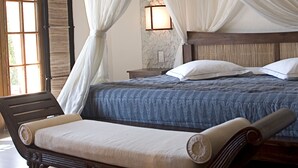 A bedroom with a bed, a wooden bench, and a window with curtains. - Domaine du Val de Sault (Sault)