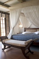 Un dormitorio con una cama, un banco de madera y una ventana con cortinas.