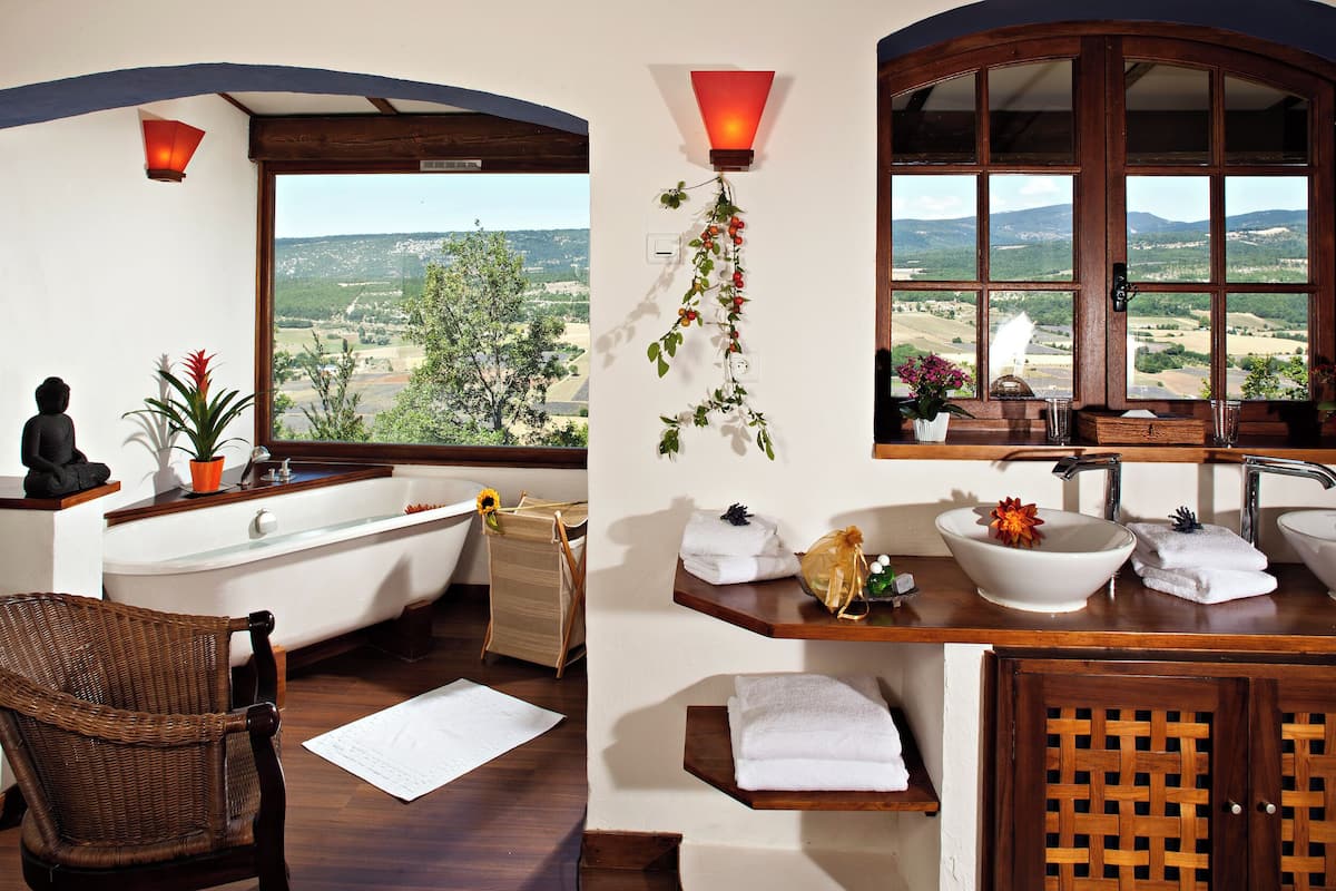 A bathroom with a bathtub, a sink, and a window offering a scenic view.