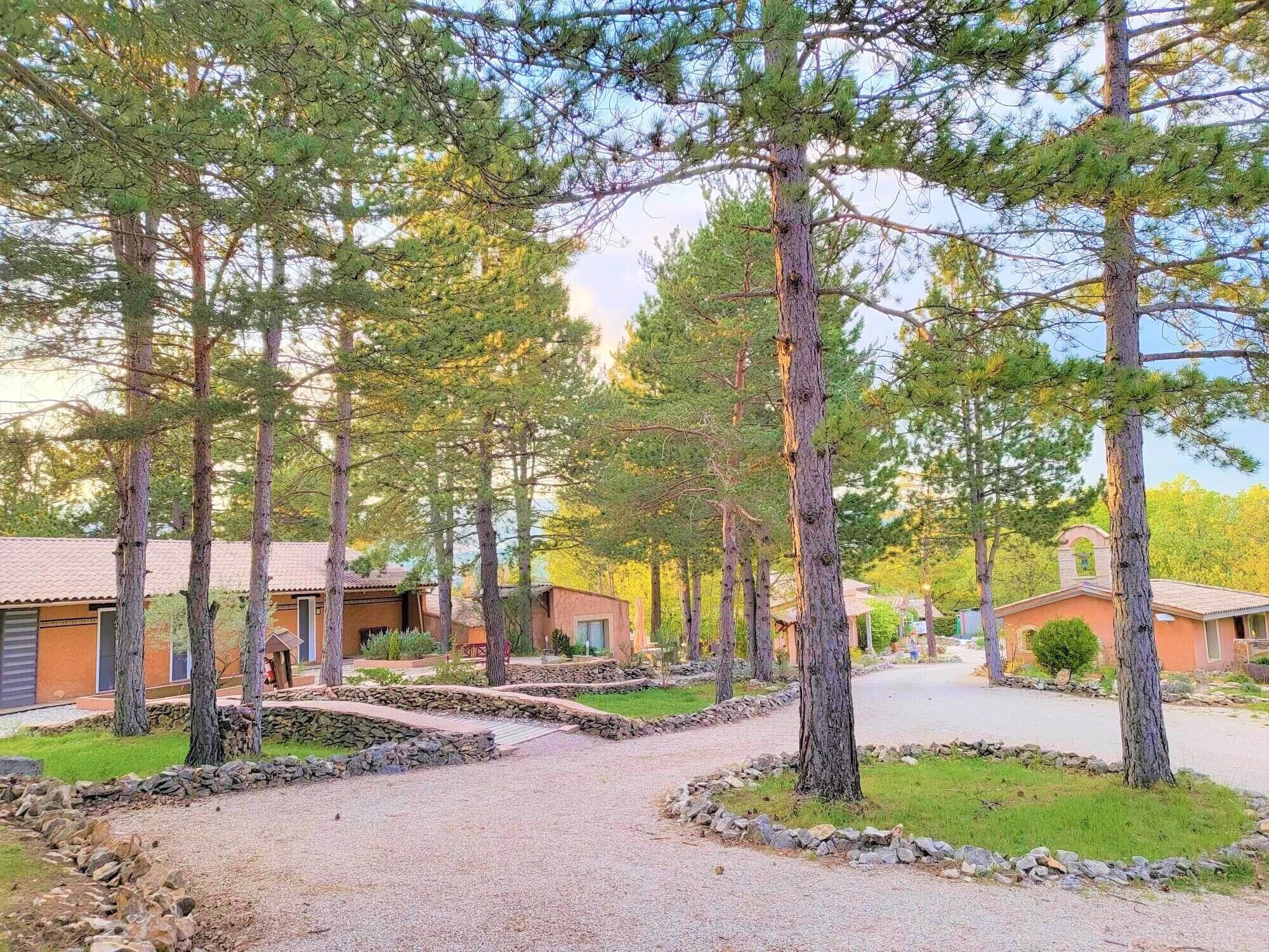 A pathway leading to a row of cabins with a stone border and a grassy area.