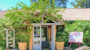 A rustic building with a tiled roof, a wooden door, and a small porch area. There are potted plants and a stone wall in front. - Domaine du Val de Sault (Sault)