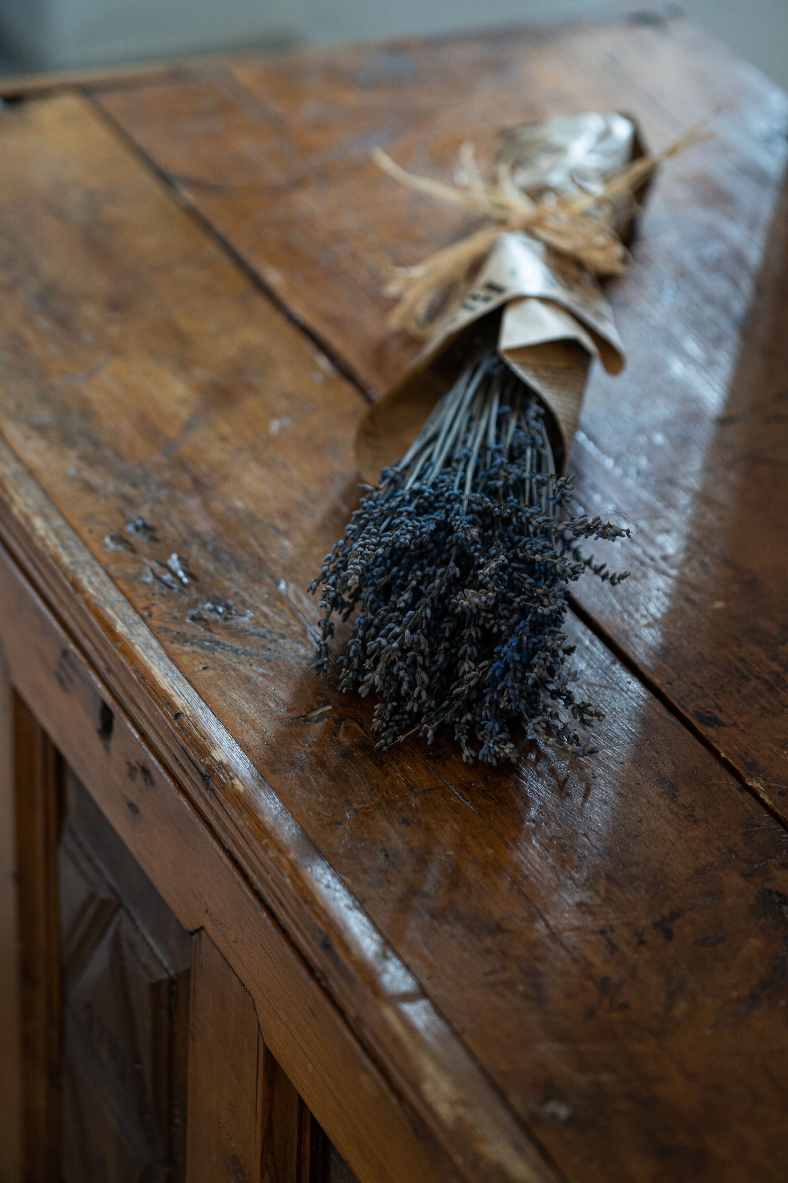 A rustic wooden table with a bundle of dried lavender tied with twine.