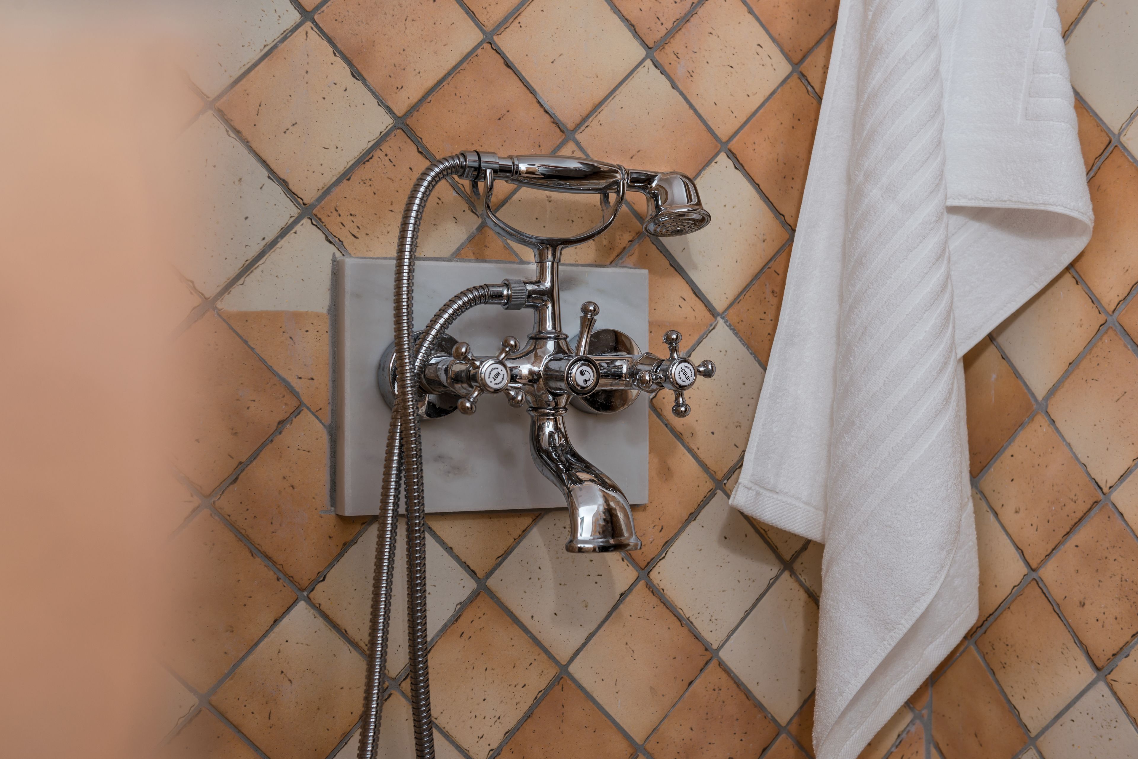A bathroom with a shower, a towel, and a tiled floor.