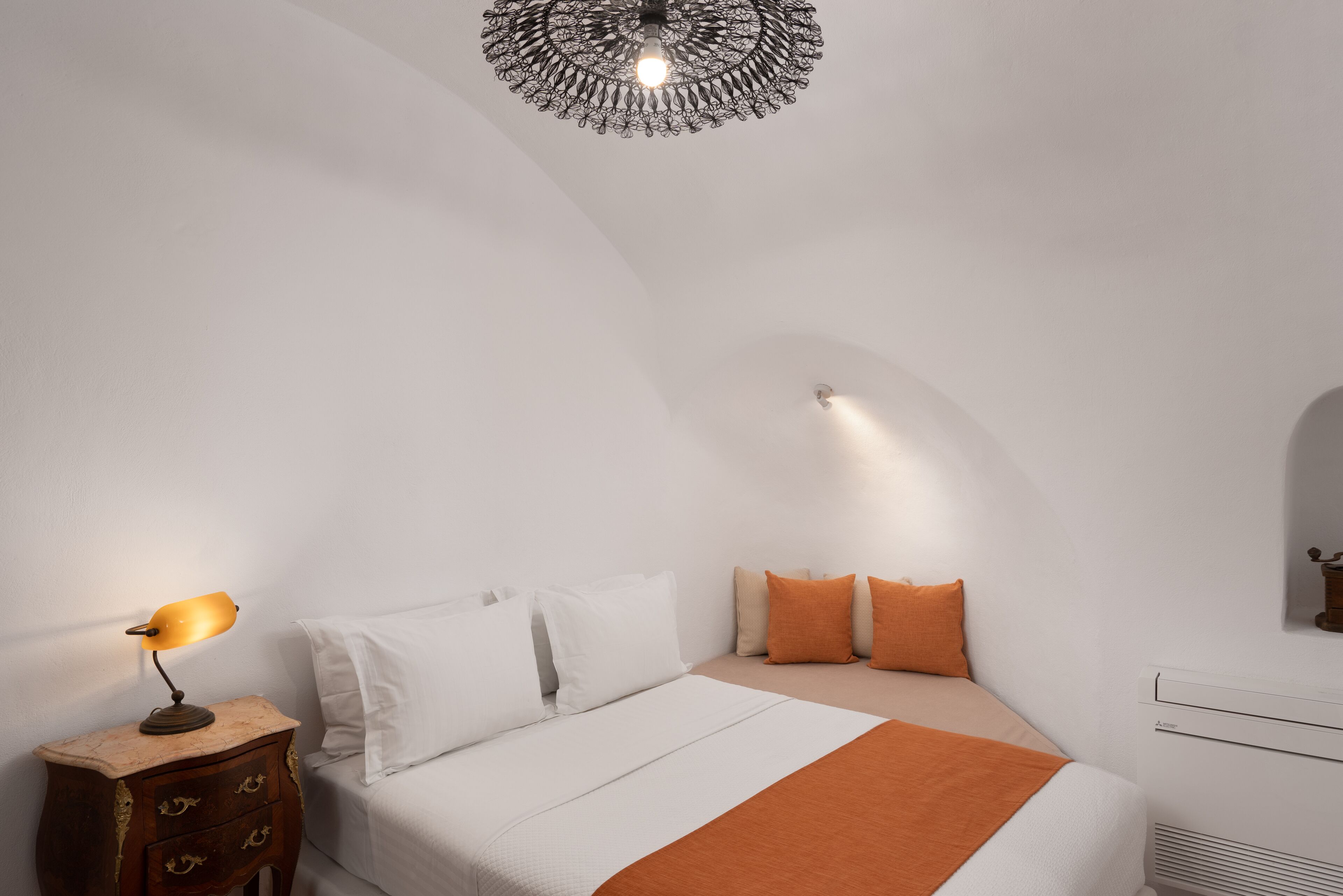 Un dormitorio con una cama, una mesita de noche con lámpara y un diseño de techo único.
