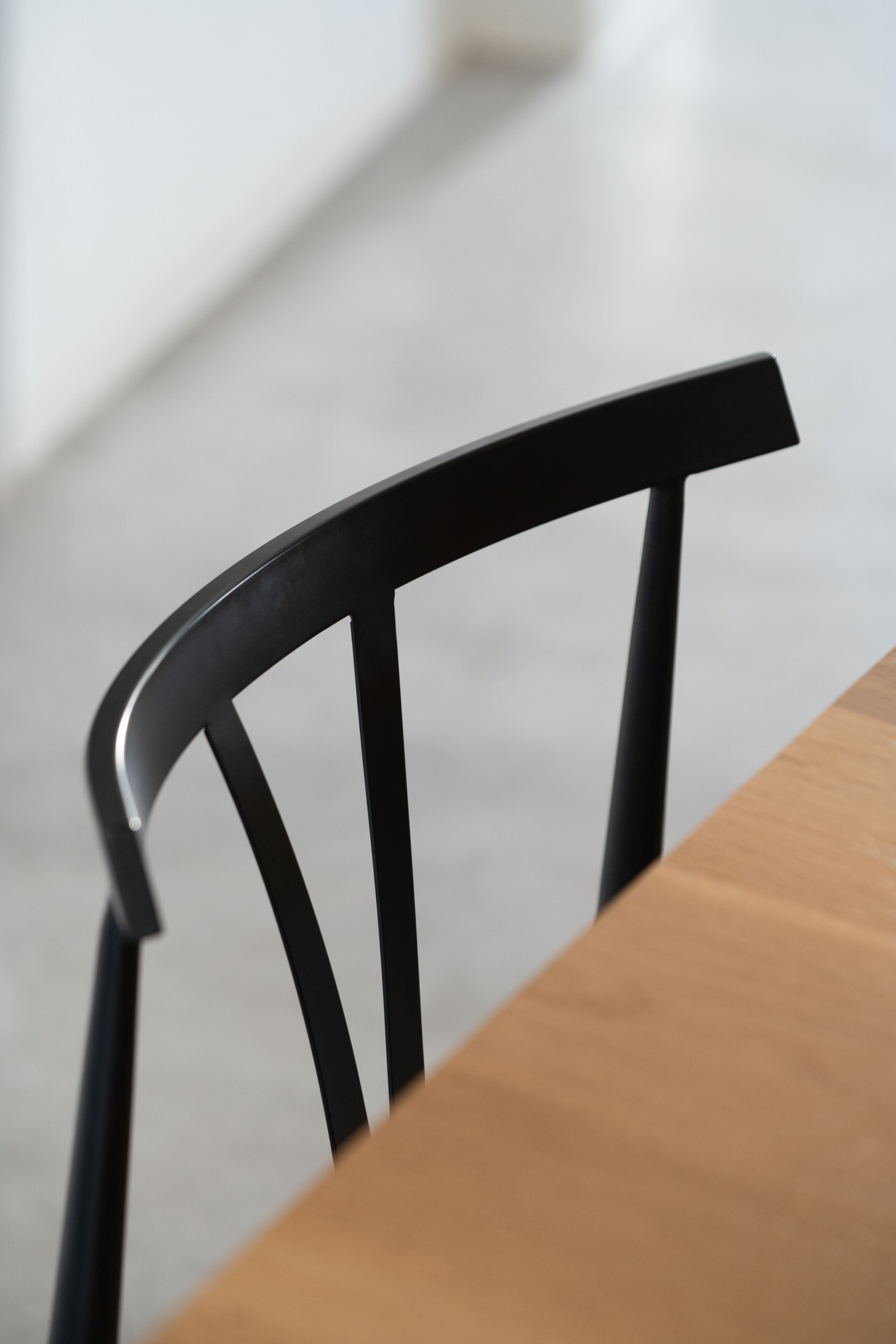 A close-up of a wooden table and a black chair.
