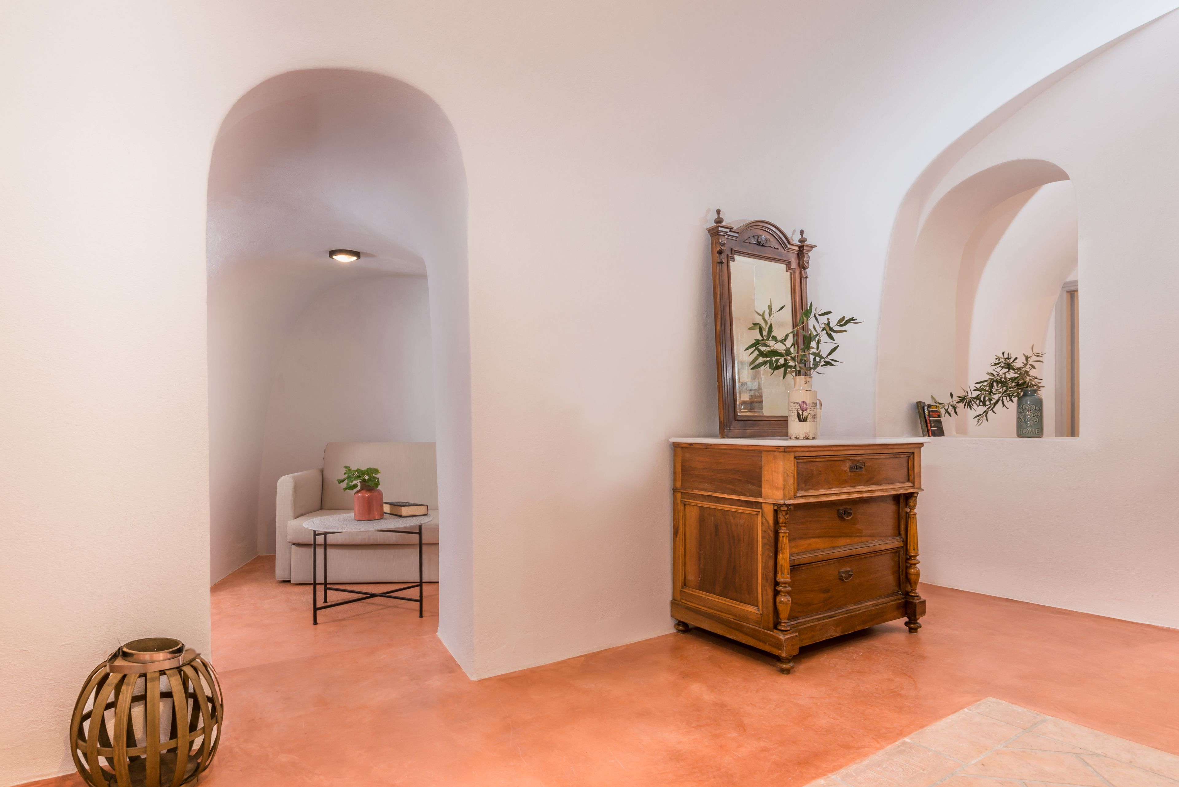A hallway with a wooden dresser, a mirror, and a chair with a plant.