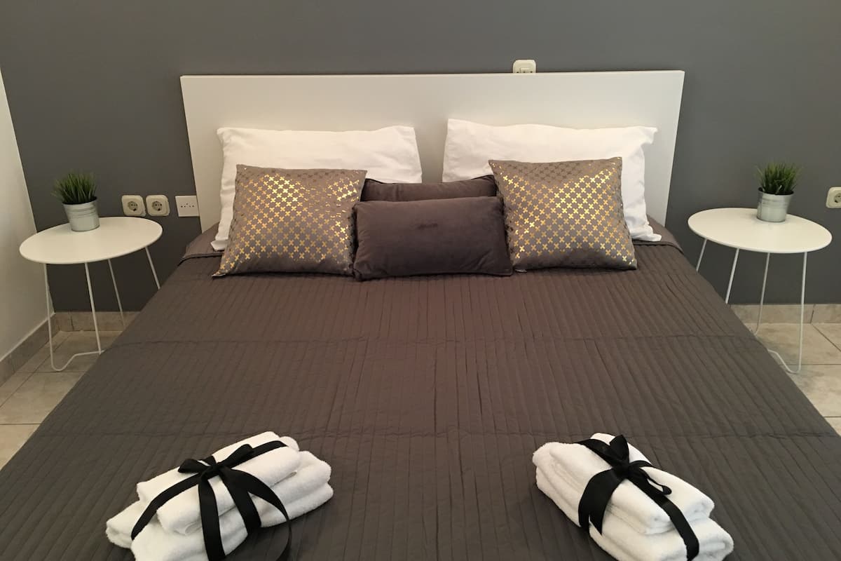 A modern hotel room with a large bed, two bedside tables with potted plants, and neatly folded towels on the bed.