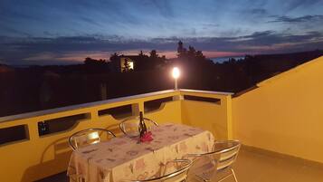 Ein Balkon mit einem Tisch für zwei Personen, einer Flasche und einer Kerze.
