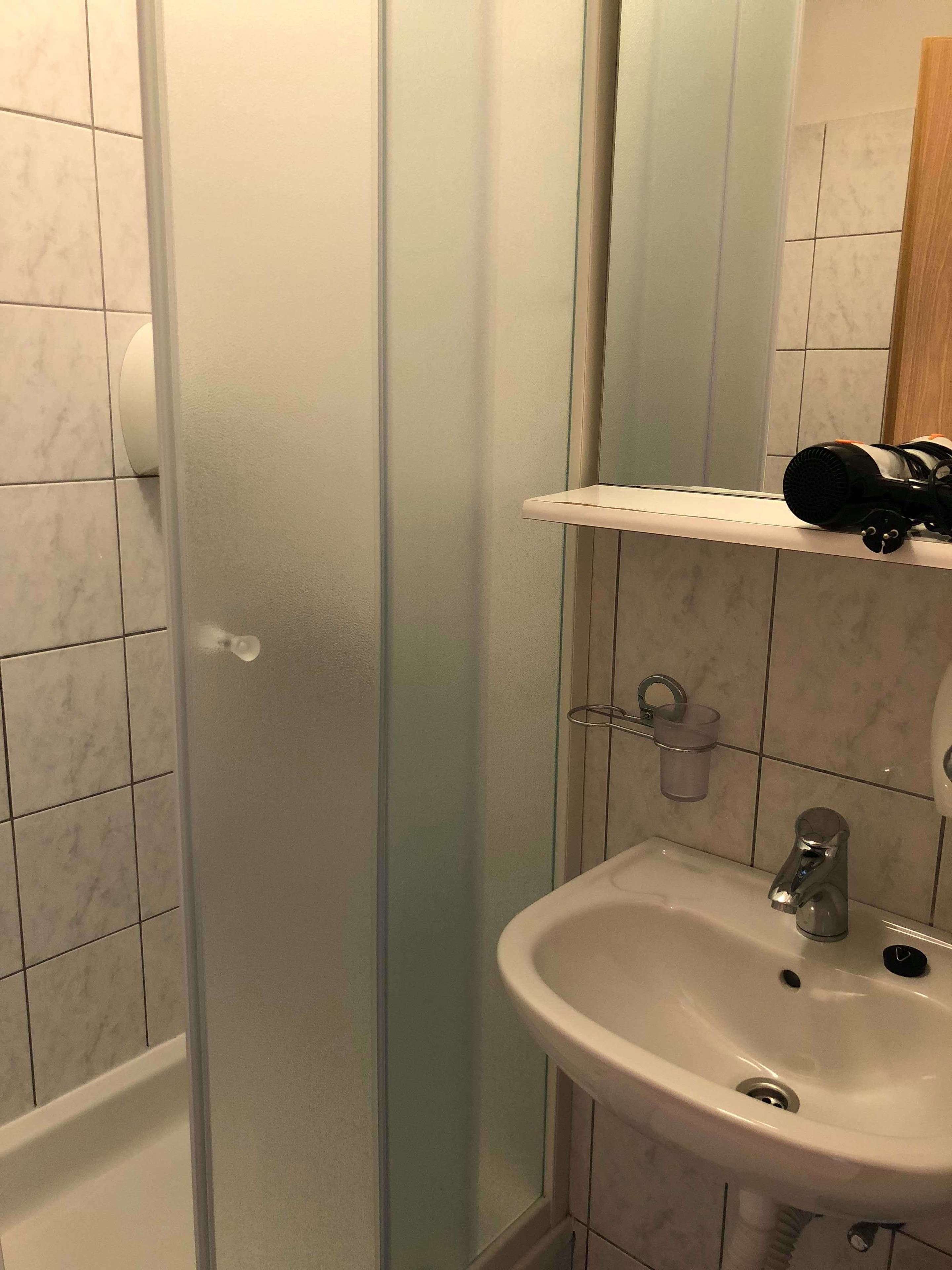 A bathroom with a white sink, a mirror, and a shower enclosure.