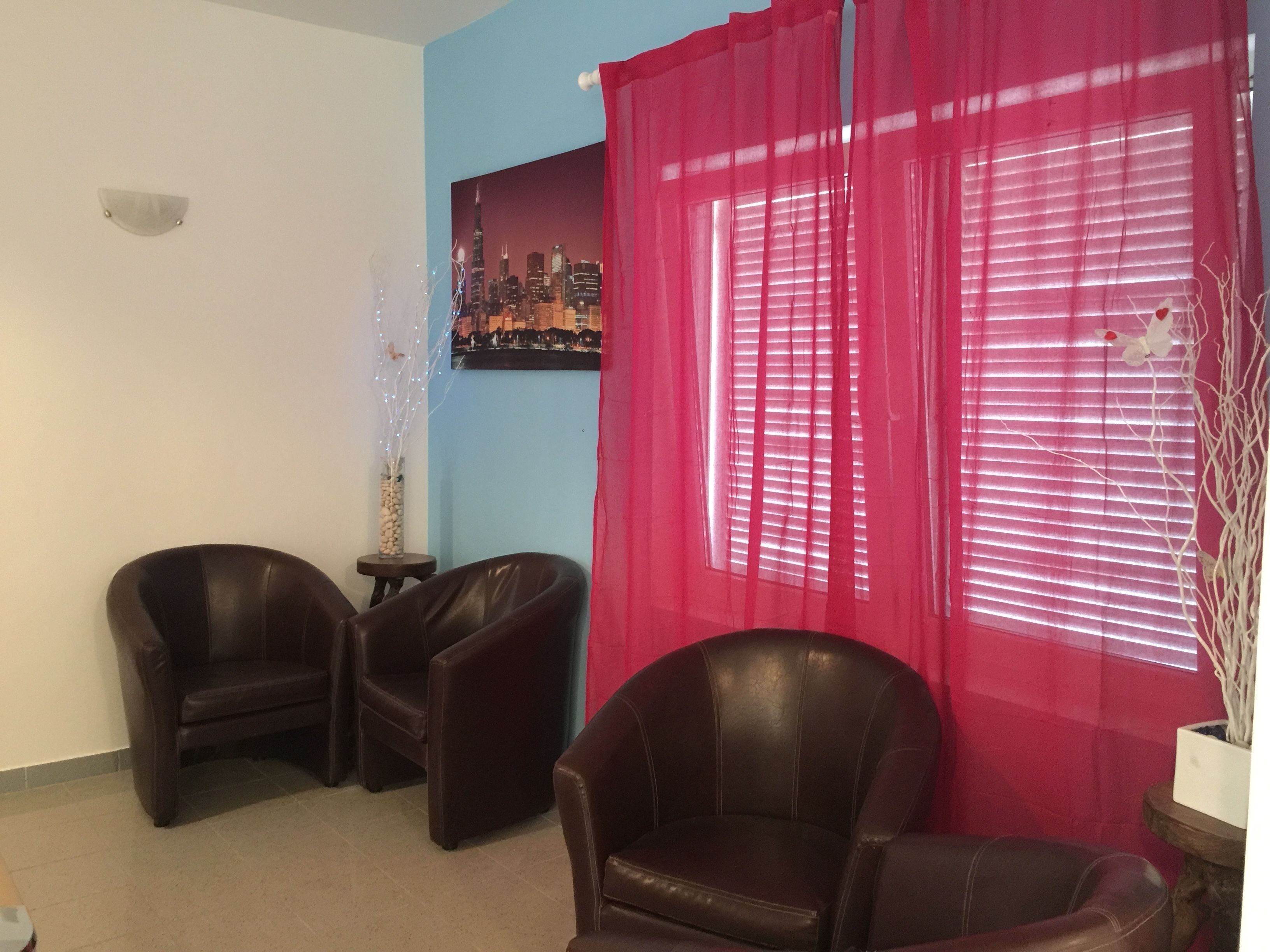 Un salón con dos sillones de cuero, una mesita, un jarrón decorativo y una pintura de un paisaje urbano en la pared.