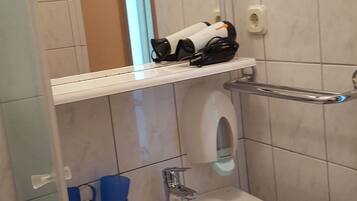 A bathroom with a white sink, a mirror, and a shelf with toiletries.
