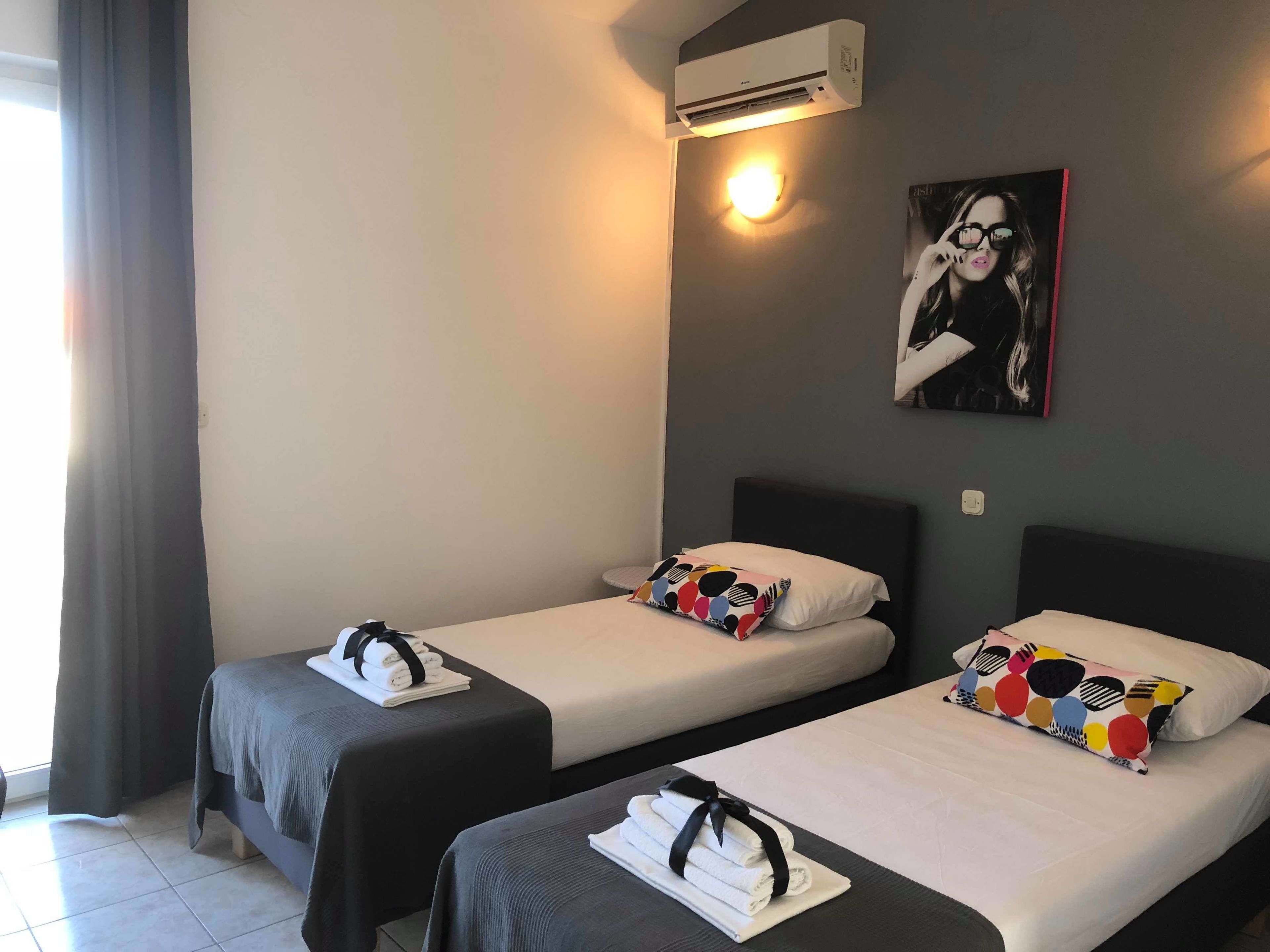 A hotel room with two beds, each with a pillow and a towel.